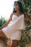 Woman in a beige linen outfit sitting against a natural background