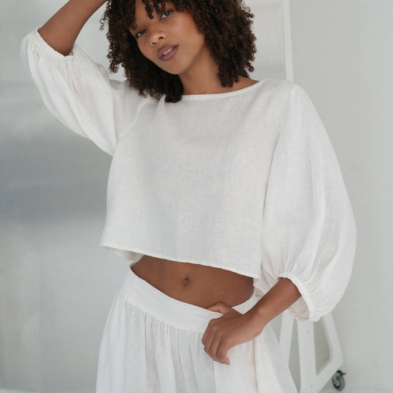 Woman wearing a white linen outfit in a minimalistic setting