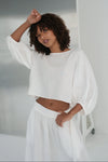 Woman wearing a white linen outfit in a minimalistic setting