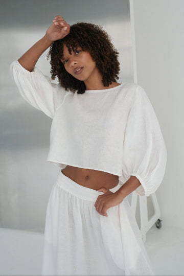 Woman wearing a white linen outfit in a minimalistic setting