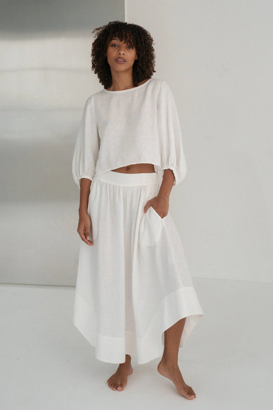 Woman wearing a white linen outfit against a plain background