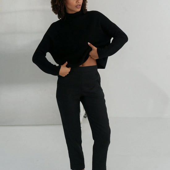 Person wearing a black linen trousers against a white background