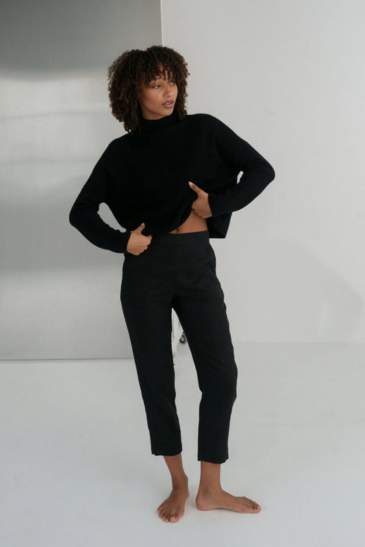 Person wearing a black linen trousers against a white background