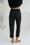Person wearing black linen trousers against a white background