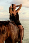 Woman in a black dress sitting on a horse with a scenic background