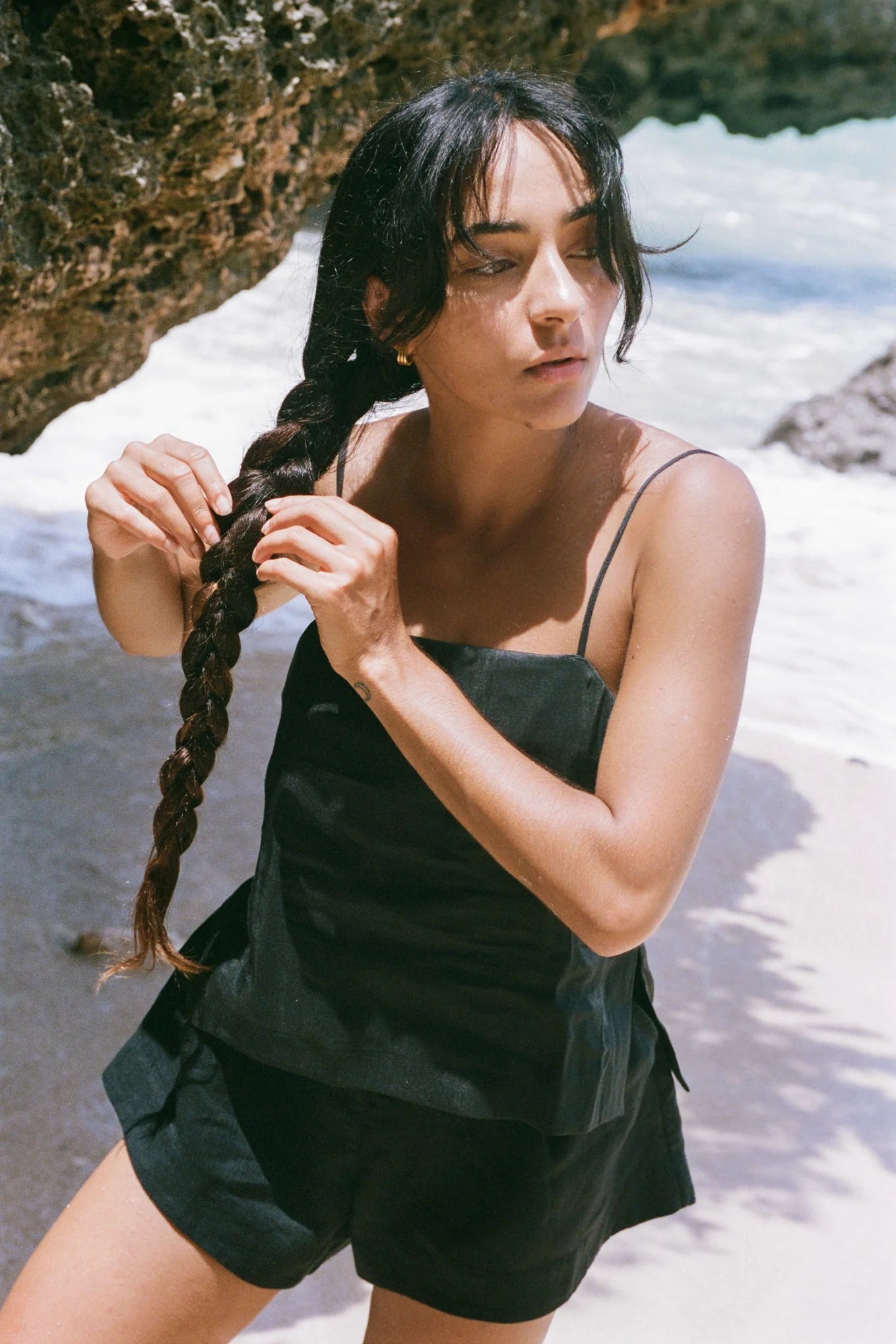 Woman braiding her hair on a beach