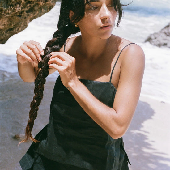 Woman braiding her hair on a beach