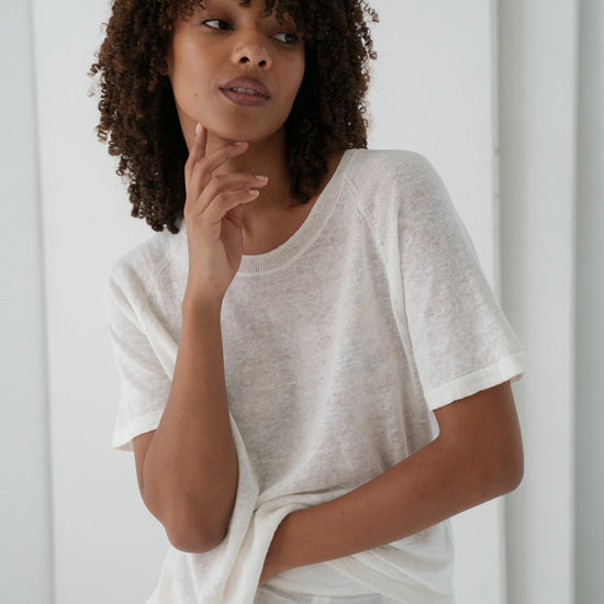 Woman wearing a white top against a plain background