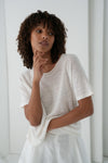 Woman wearing a white top against a plain background