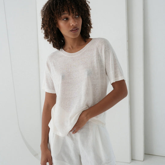 Woman wearing a white outfit standing against a white background