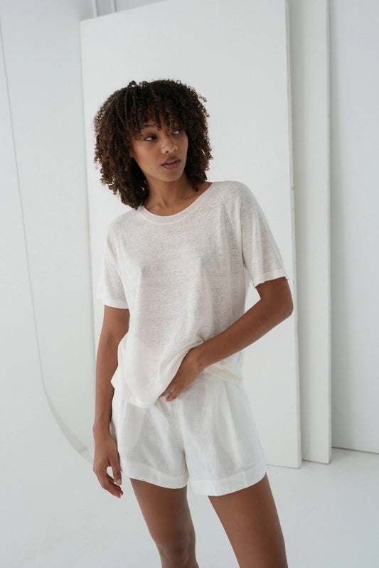 Woman wearing a white outfit standing against a white background