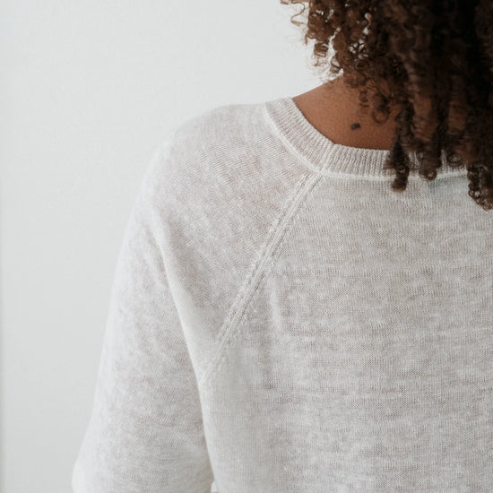 Person wearing a light gray sweater against a white background