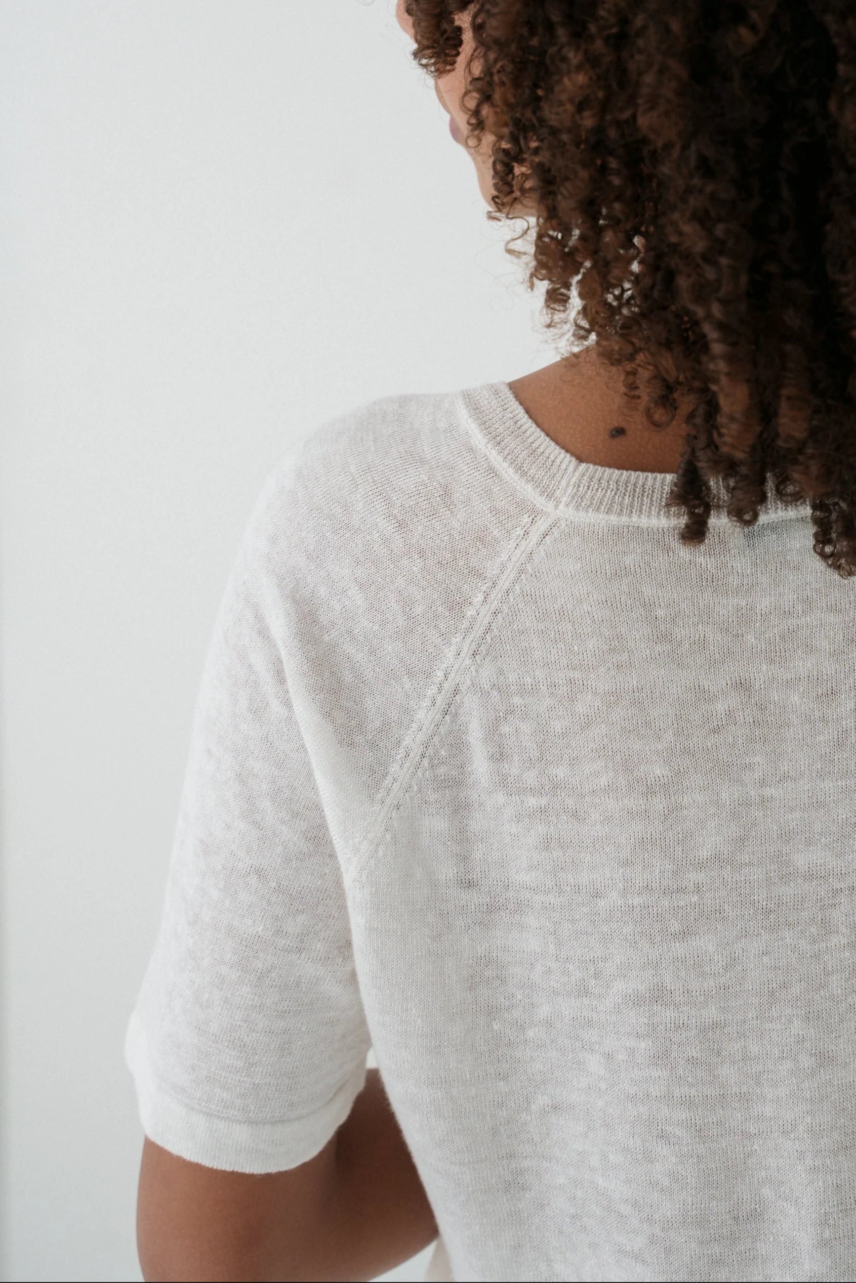 Person wearing a light gray sweater against a white background