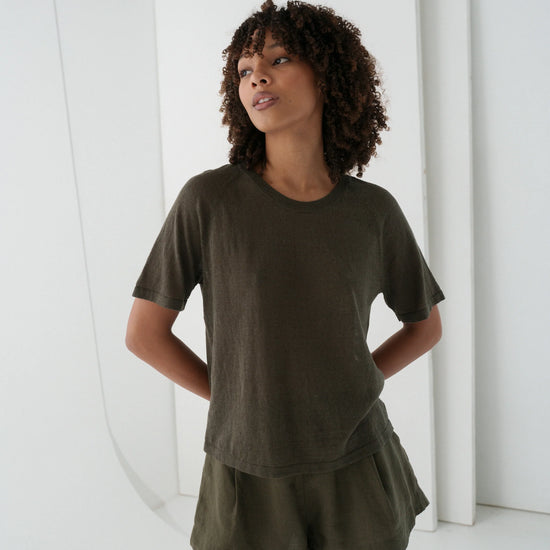 Woman wearing an olive green outfit standing against a white background