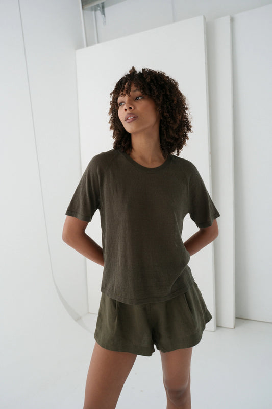 Woman wearing an olive green outfit standing against a white background