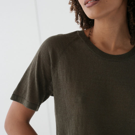 Person wearing a dark green t-shirt against a white background