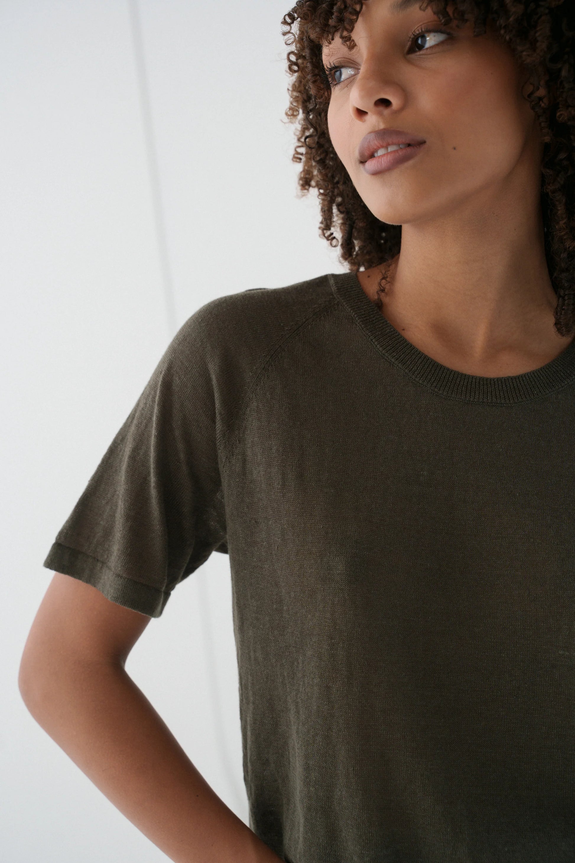 Person wearing a dark green t-shirt against a white background