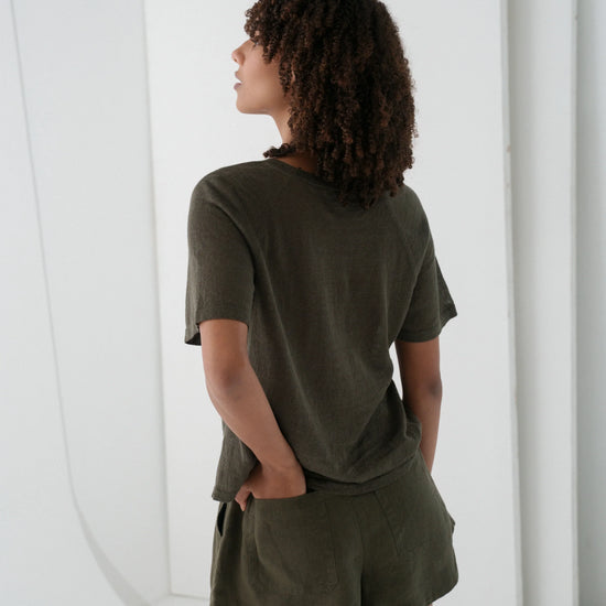 Person wearing an olive green outfit standing against a white background