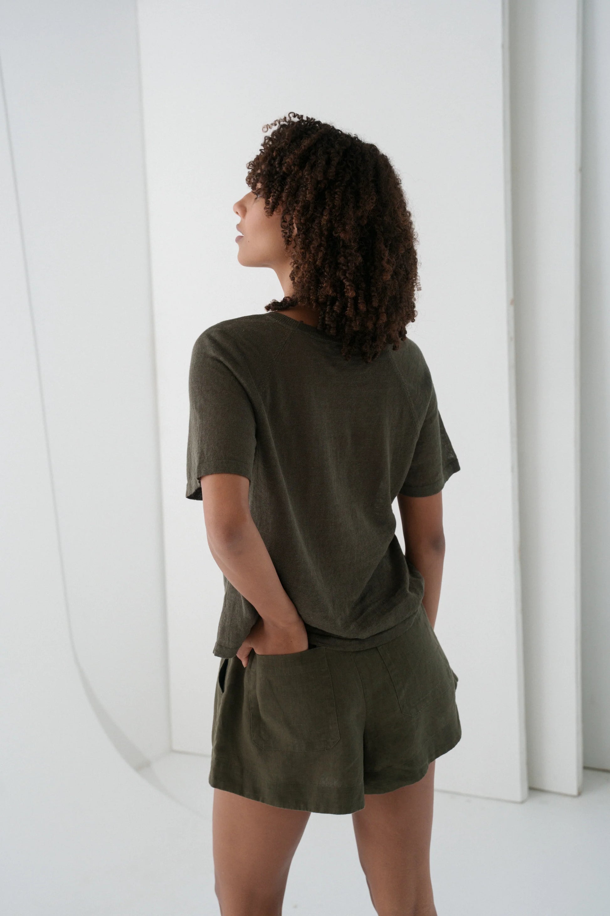 Person wearing an olive green outfit standing against a white background