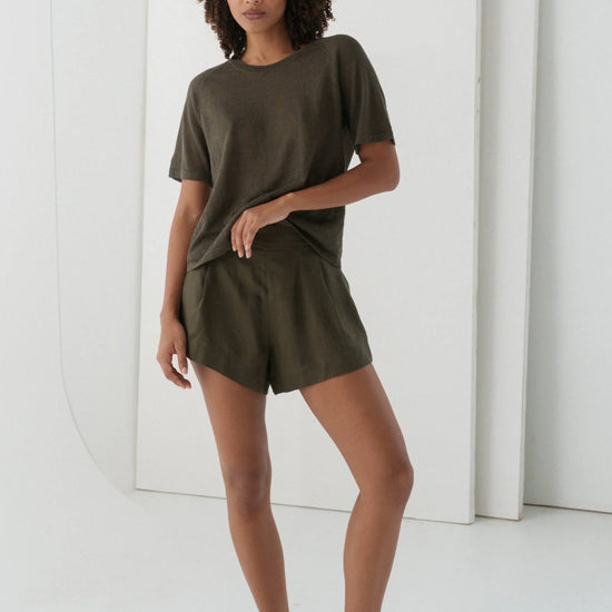 Woman wearing an olive green outfit against a white background