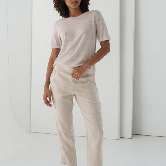 Woman wearing a beige t-shirt and pants in a minimalistic setting