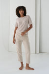 Woman wearing a beige t-shirt and pants in a minimalistic setting