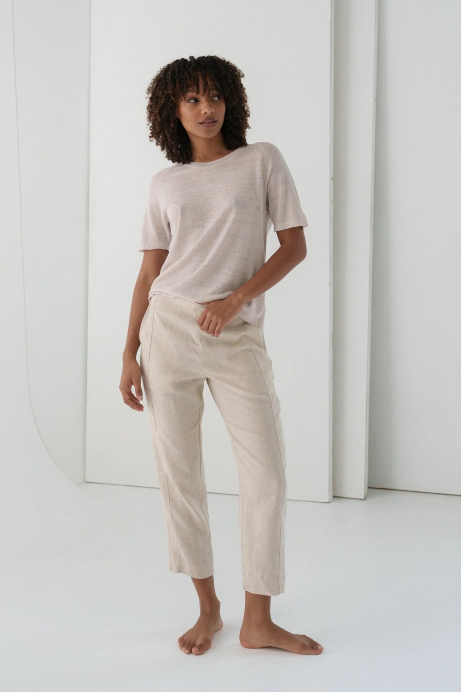 Woman wearing a beige t-shirt and pants in a minimalistic setting