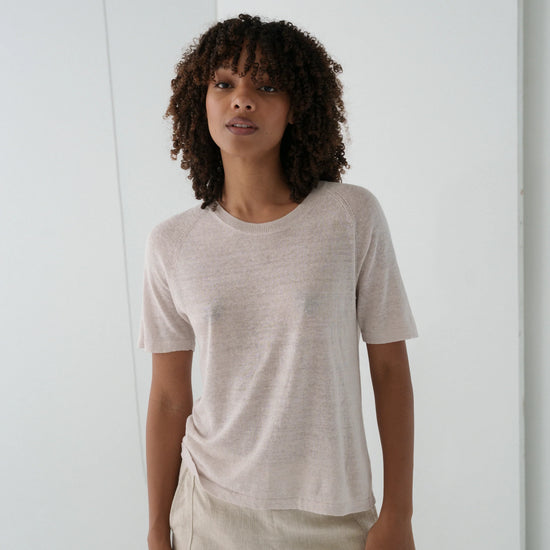 Woman wearing a beige t-shirt and pants in a minimalistic setting