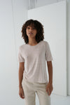 Woman wearing a beige t-shirt and pants in a minimalistic setting