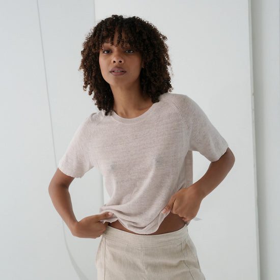 Woman wearing a light-colored t-shirt and pants in a minimalistic setting