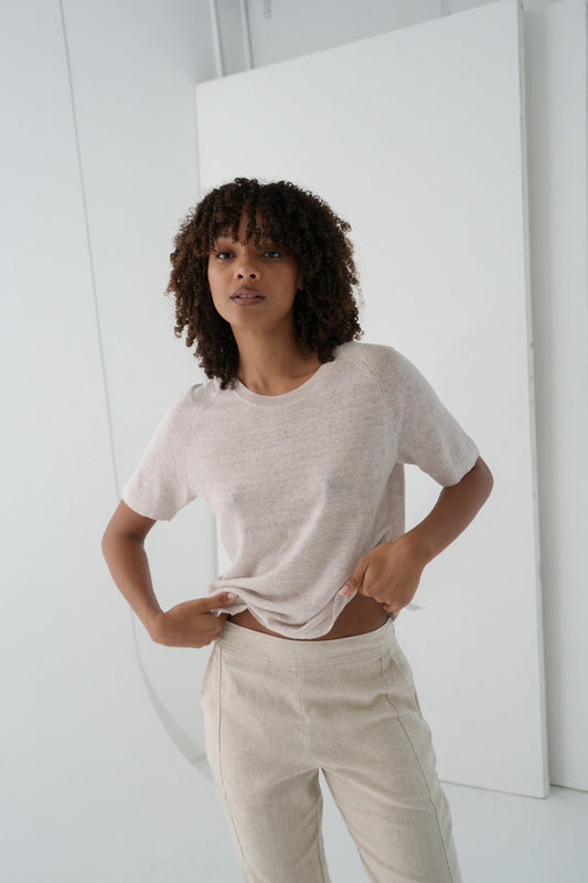 Woman wearing a light-colored t-shirt and pants in a minimalistic setting