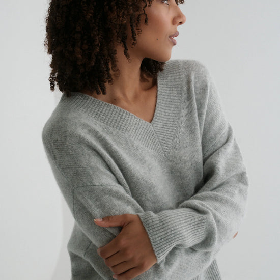 Woman wearing a gray sweater against a white background
