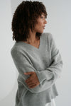 Woman wearing a gray sweater against a white background