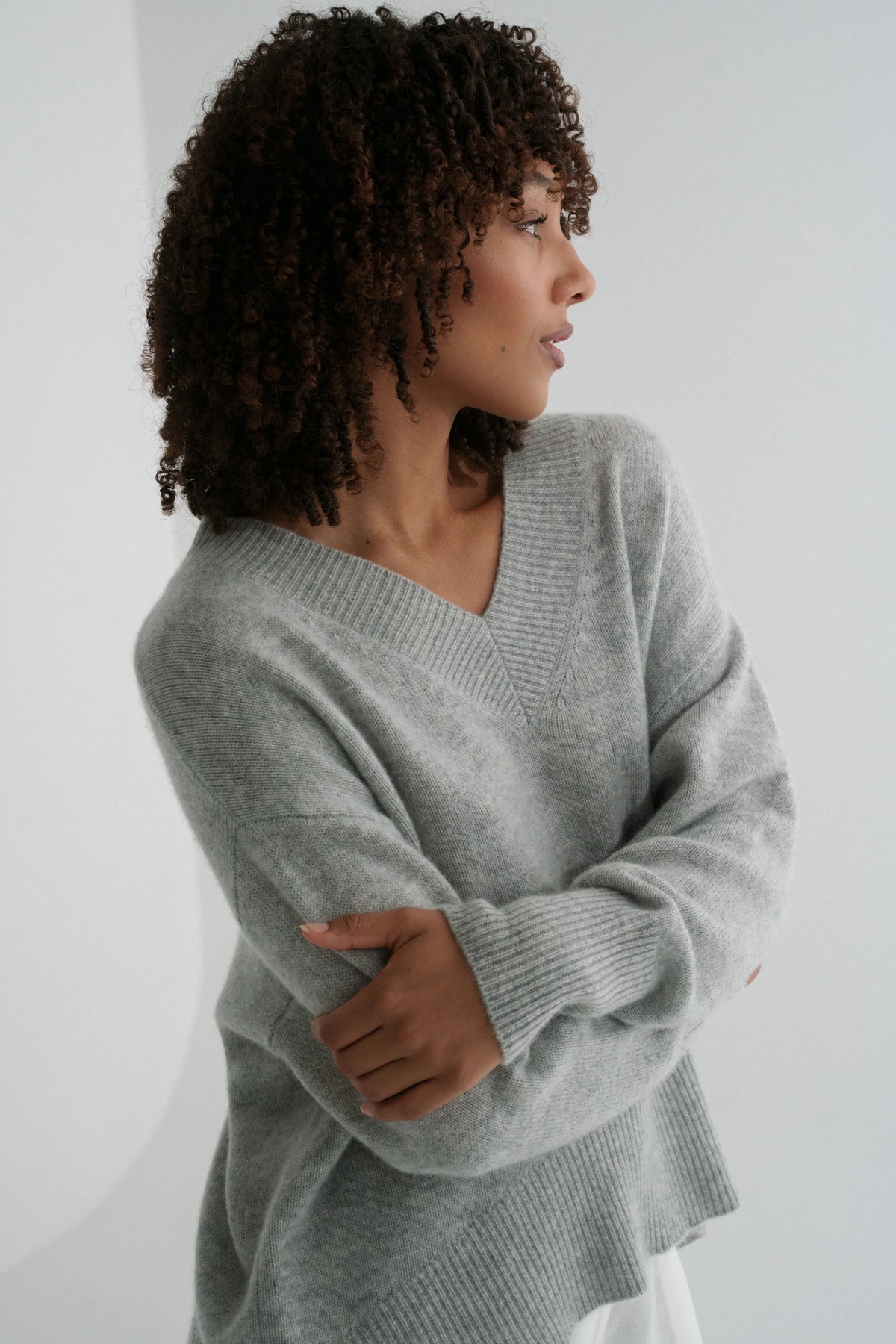 Woman wearing a gray sweater against a white background