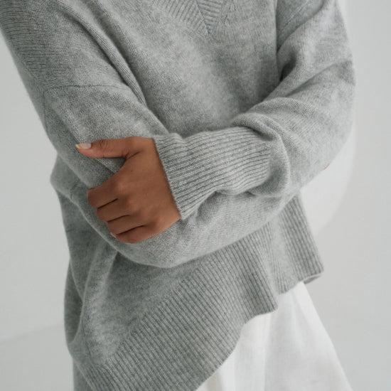 Person wearing a gray sweater against a white background