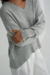 Person wearing a gray sweater against a white background