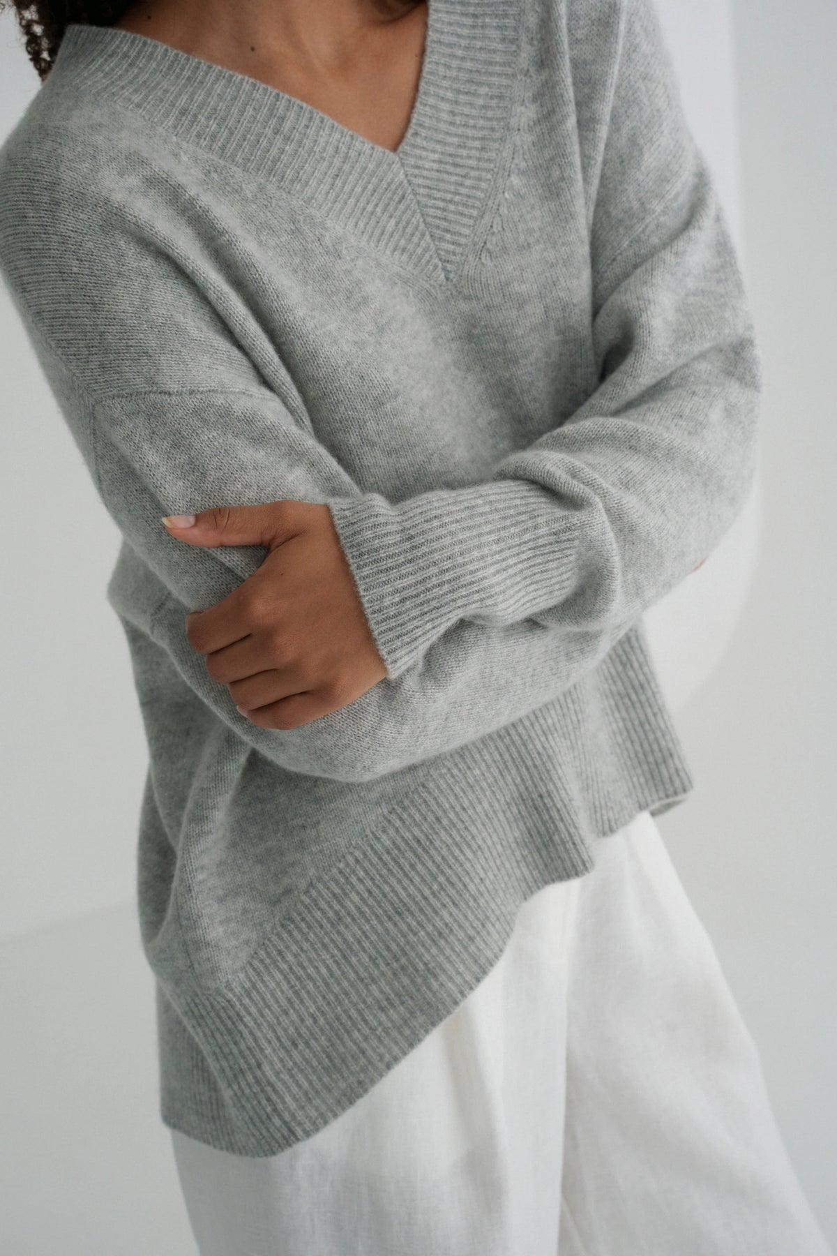 Person wearing a gray sweater against a white background