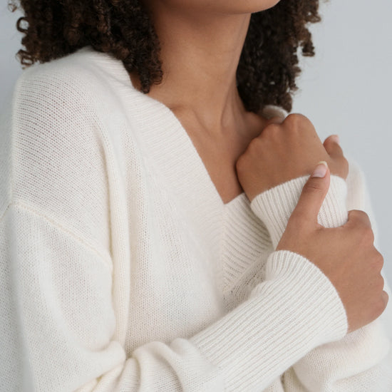 Woman wearing a white sweater against a neutral background