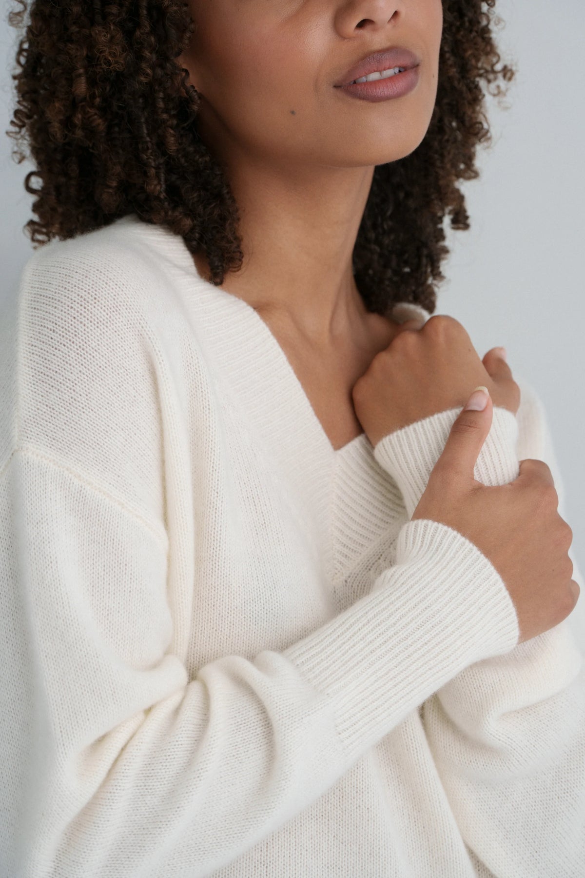 Woman wearing a white sweater against a neutral background