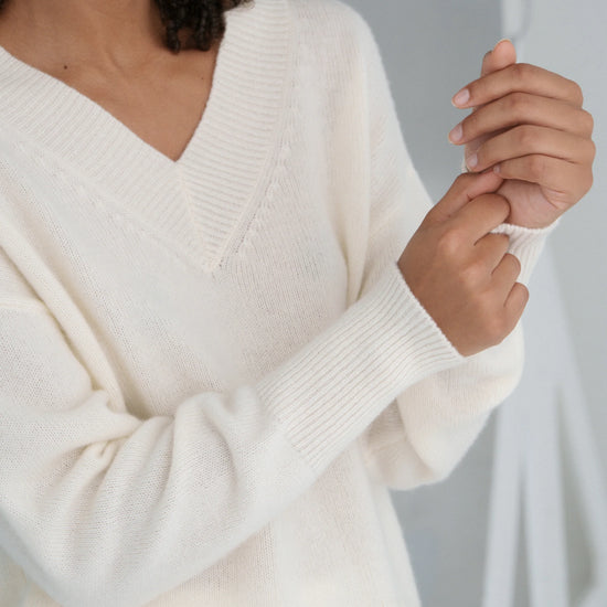 Person wearing a cream-colored sweater with a blurred background