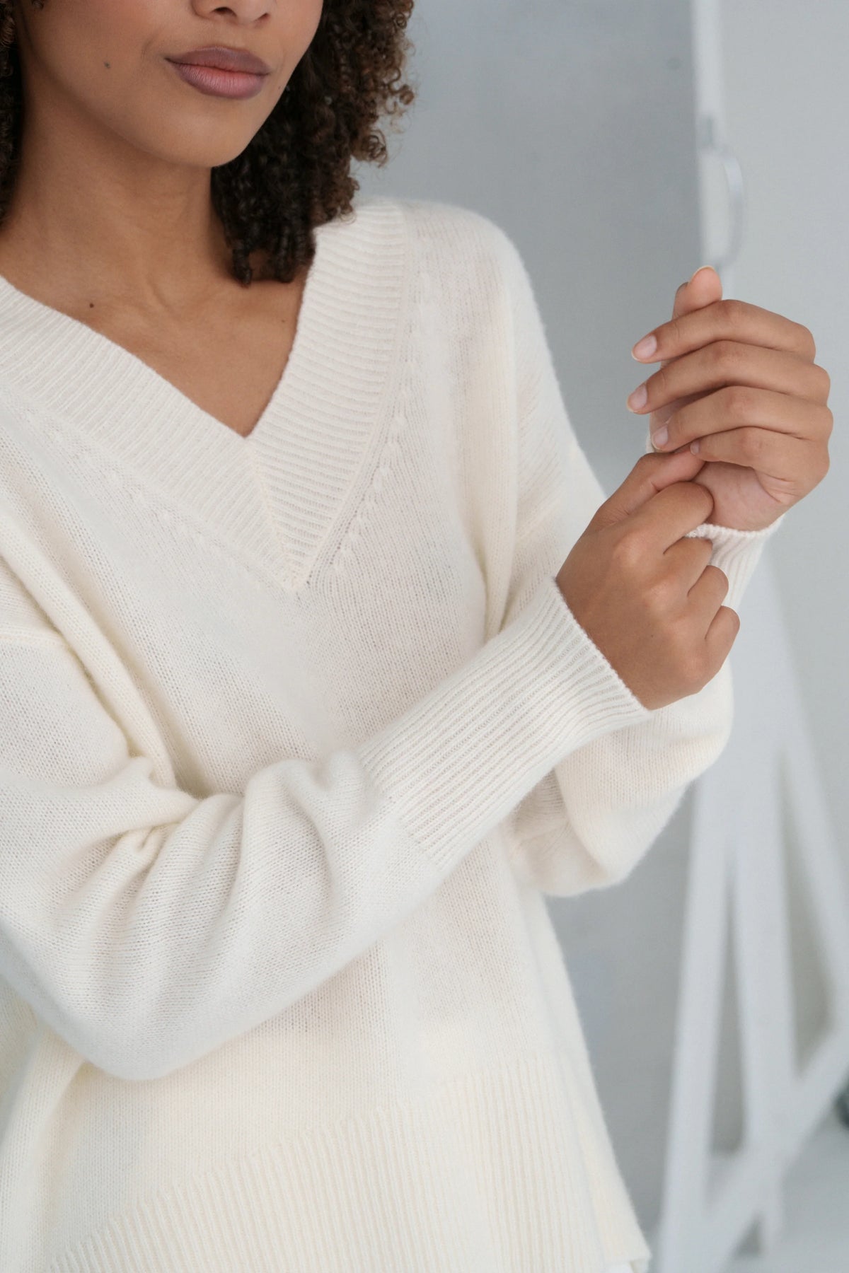 Person wearing a cream-colored sweater with a blurred background