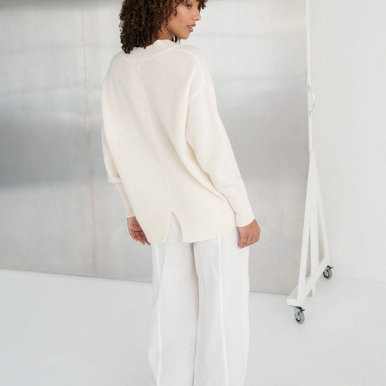 Person wearing a white outfit standing against a neutral background