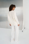 Person wearing a white outfit standing against a neutral background