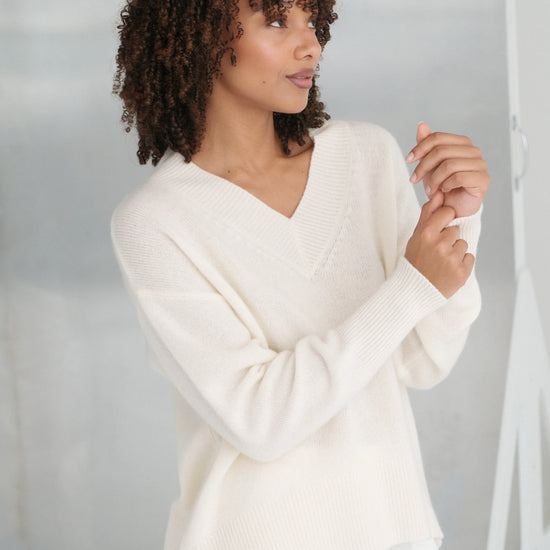 Woman wearing a white sweater against a plain background