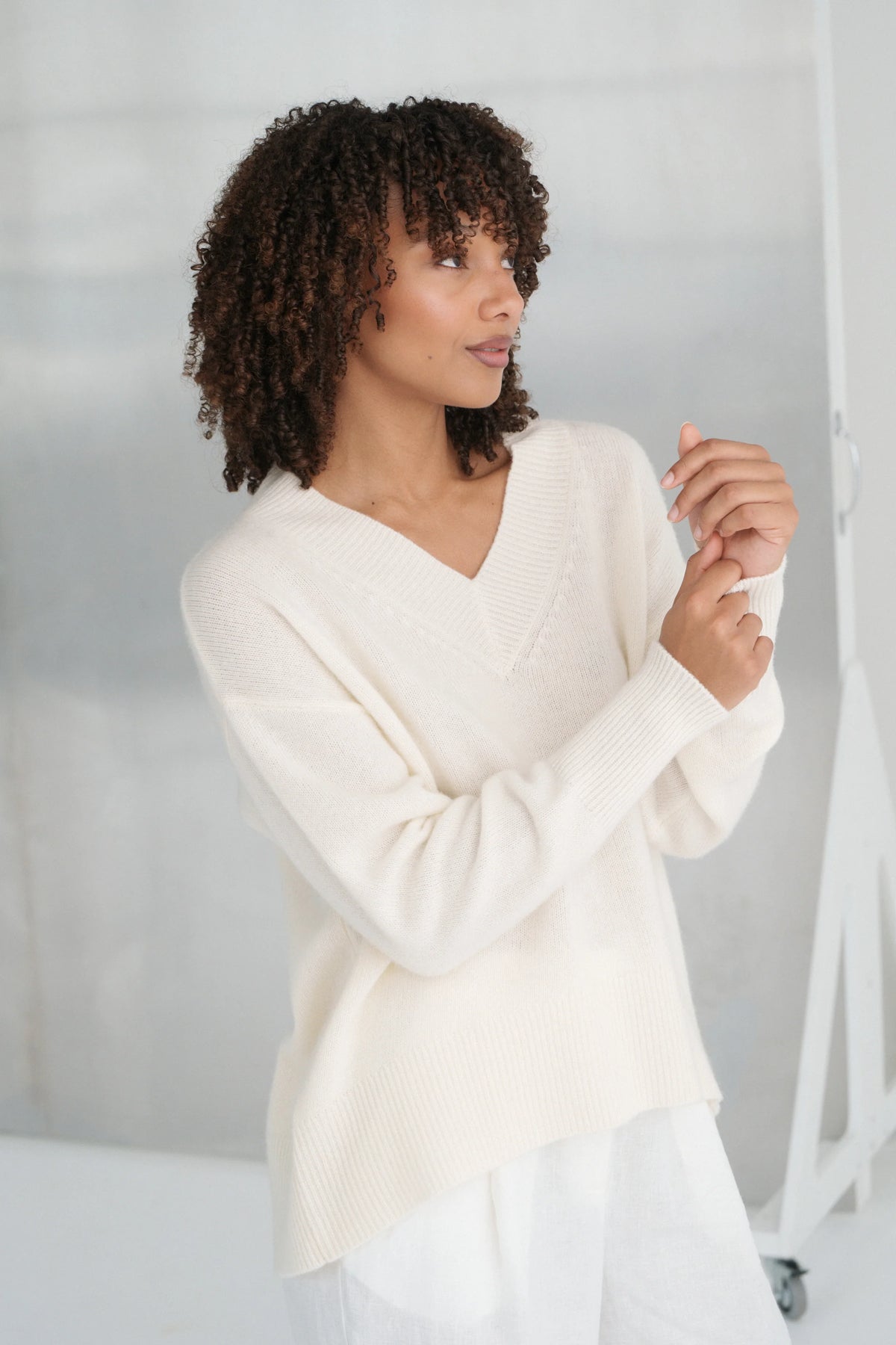 Woman wearing a white sweater against a plain background