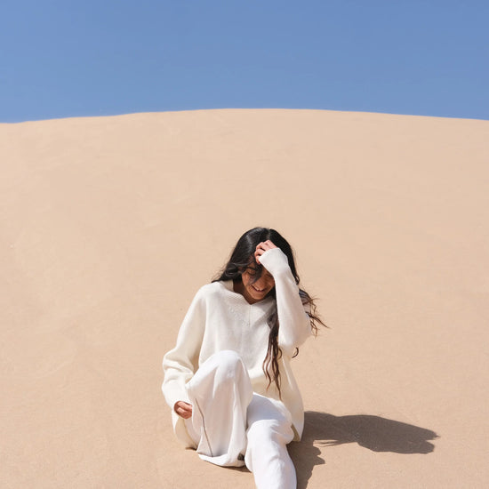 Person sitting on a sand dune with a clear blue sky