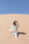 Person sitting on a sand dune with a clear blue sky
