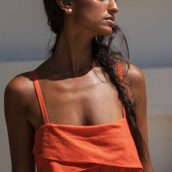 Woman wearing an orange linen dress with a neutral background