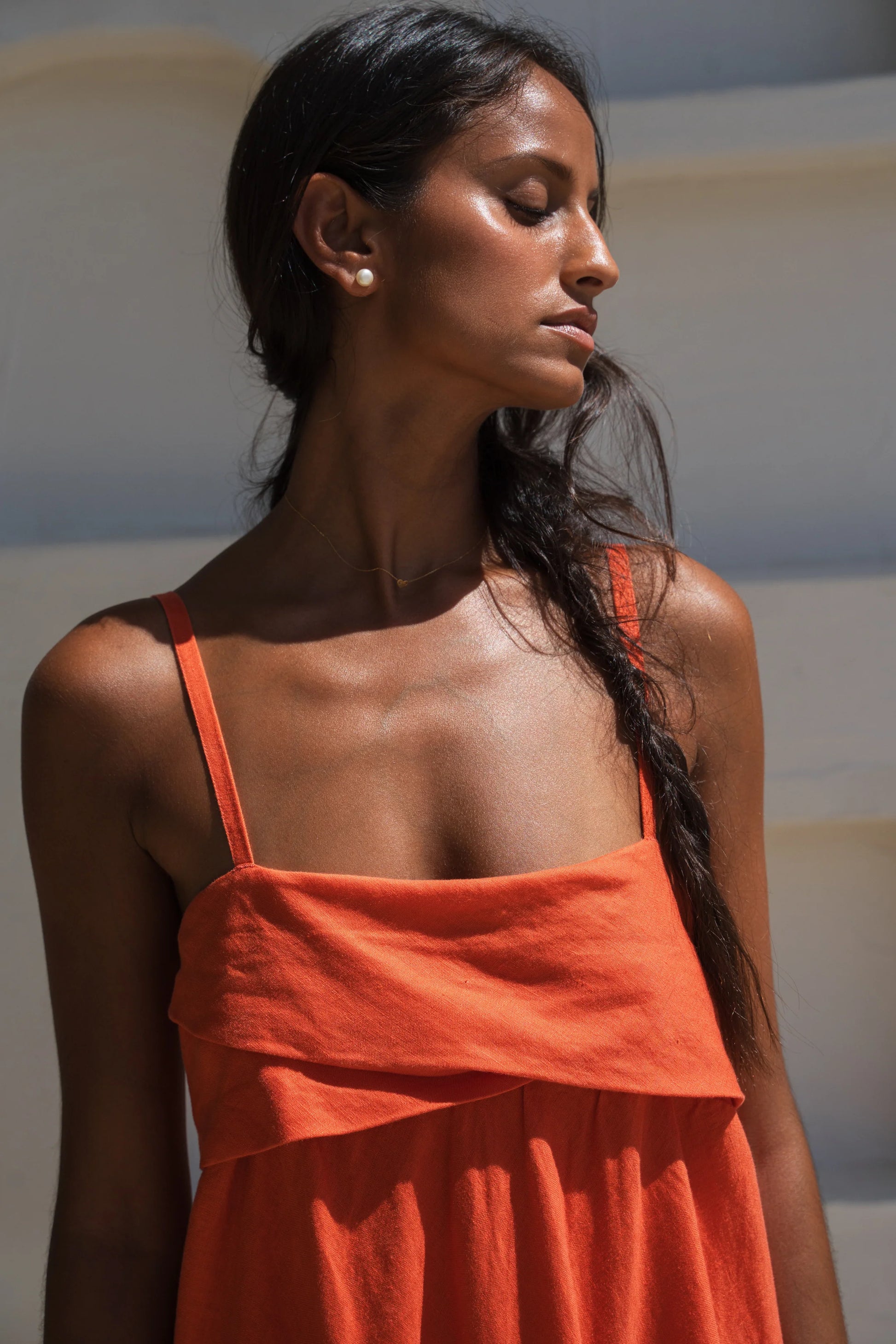 Woman wearing an orange linen dress with a neutral background