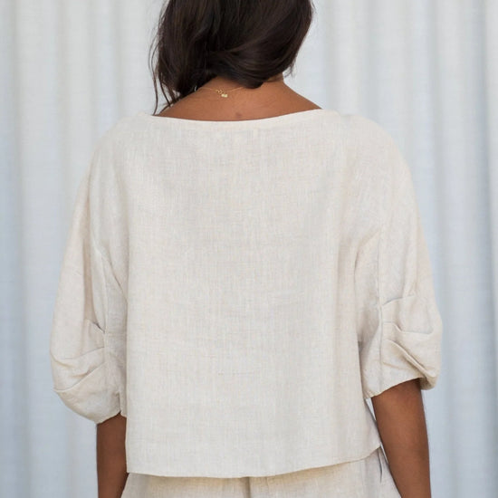 Person wearing a beige outfit against a white curtain background rear view from Lilly Pilly